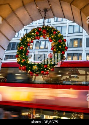 COURONNE DE NOËL FLOU DE BUS LONDONIEN décorée de boules de luxe suspendues à l'extérieur du Ritz Hotel Piccadilly London UK. Bus rouges flous passant avec des fenêtres de bureau derrière Piccadilly London UK Banque D'Images