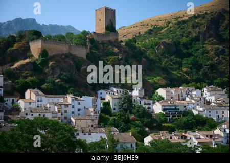Un château médiéval au sommet d'une colline pittoresque entouré d'une végétation luxuriante, surplombant un beau village traditionnel blanchi à la chaux niché dans un stunnin Banque D'Images
