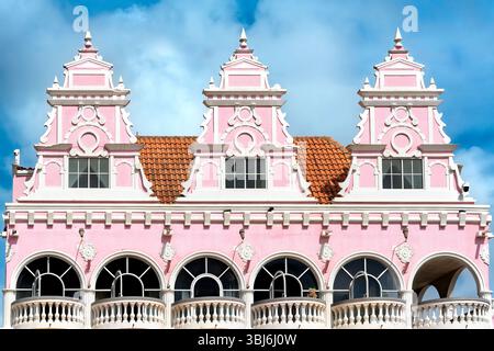 Le charme d'Oranjestad, Aruba, capturé dans ce bâtiment traditionnel hollandais. Teintes roses et design classique sous un ciel clair. Banque D'Images
