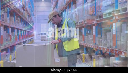 Travailleur portant un gilet de sécurité jaune vérifiant les boîtes sur la palette dans l'allée de l'entrepôt, avec planchette à pince Banque D'Images