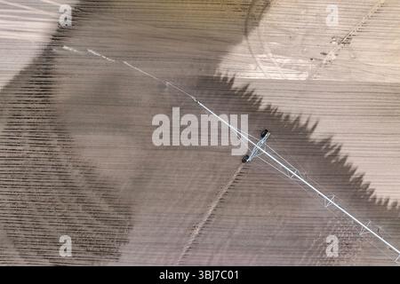 Arrosage du sol sec sur le champ agricole de culture pour les produits cultivés pendant la période de sécheresse. Système d'arrosage par sprinkleur en saison sèche Banque D'Images