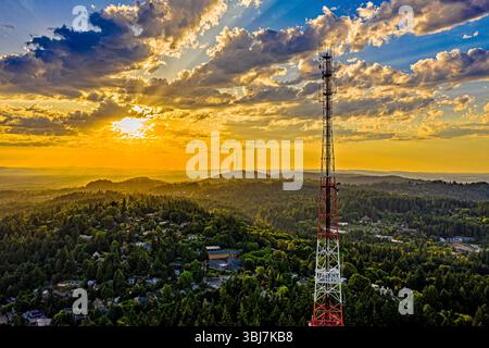 Portland, Oregon - 12 juin 2019 : une tour de radio se dresse au milieu d'une forêt luxuriante pendant un coucher de soleil vibrant, fournissant des services de communication essentiels Banque D'Images