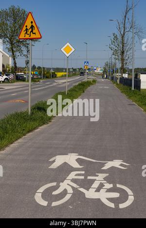 Piste piétonne et cyclable le long de la route de banlieue avec des marquages de sécurité clairs et des panneaux de signalisation. Sécurité routière, protection des enfants et parcours partagés Banque D'Images