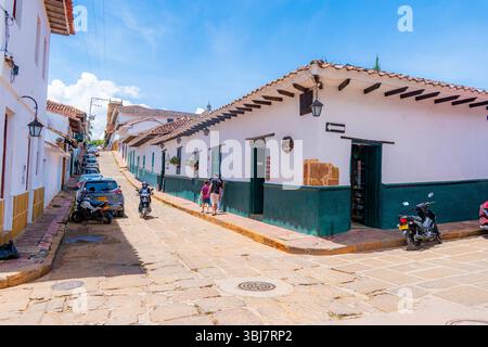 Barichara, Santander, Colombie, 11 octobre 2024. Une maison coloniale blanche avec une base verte se dresse bien en évidence sur le coin d'une rue pavée th Banque D'Images