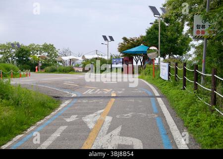 Incheon, Corée du Sud - 19 mai 2025 : les cyclistes approchent du centre de certification de l'écluse d'Ara Hangang le long d'un chemin clairement balisé, passant sous la LIG solaire Banque D'Images