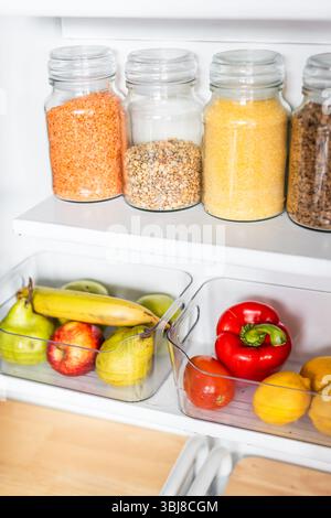 petit garde-manger organisé avec des bocaux transparents assortis remplis de céréales, légumineuses, épices et produits frais dans des récipients, alimentation saine, maison rangée, organi Banque D'Images