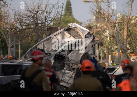 Rishon LeZion, Israël. 14 juin 2025. Un véhicule de construction retire une voiture endommagée après qu'un missile iranien a frappé Rishon LeZion, tuant au moins deux personnes et en blessant plusieurs autres. Crédit : Ilia Yefimovich/dpa/Alamy Live News Banque D'Images