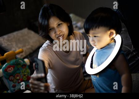 Maman et tout-petit joue avec Une lumière annulaire sur son cou, fond pour la publicité et papier peint dans la scène de marche et de style de vie. Banque D'Images