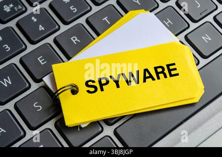 Texte de spyware sur bloc-notes blanc avec fond de clavier d'ordinateur portable. Concept d'activité hacker et arnaque Banque D'Images