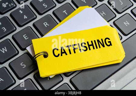 Texte catfish sur bloc-notes blanc avec fond de clavier d'ordinateur portable. Concept d'activité hacker et arnaque Banque D'Images