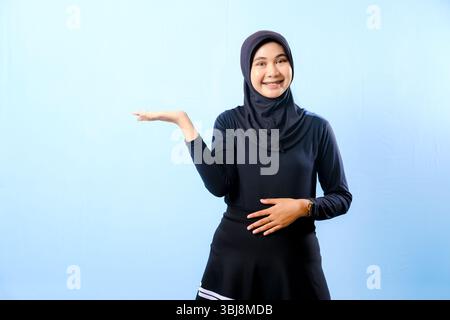 Une femme portant une robe noire et un foulard noir. Elle tient sa main en l'air Banque D'Images