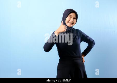 Une femme portant une robe noire et un foulard noir. Elle sourit et donne le pouce levé Banque D'Images