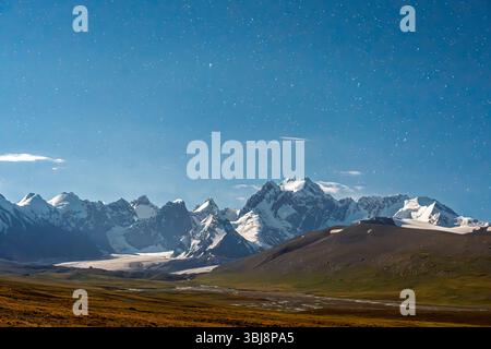 Un grand plan capturant la voie Lactée voûtant au-dessus d'une gamme majestueuse de montagnes enneigées et d'un vaste paysage sauvage la nuit Banque D'Images