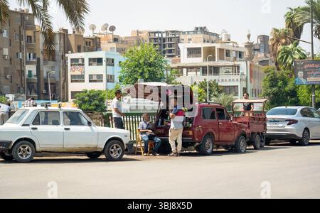 Le Caire, Egypte - 11 septembre 2023 : une scène de rue dynamique en Egypte mettant en vedette un vendeur de bord de route, des voitures anciennes et des bâtiments urbains. Banque D'Images
