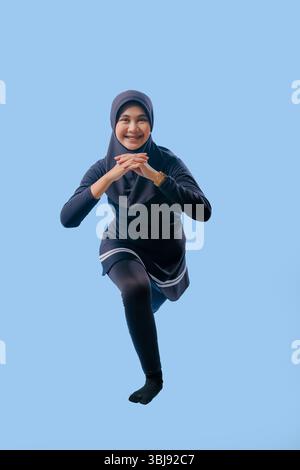 Une femme dans une tenue noire fait une pose de yoga. Elle porte une jupe noire et des chaussettes noires Banque D'Images