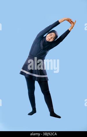 Une femme dans une tenue noire étire ses bras sur le côté. Elle porte des chaussettes noires et un pantalon noir Banque D'Images