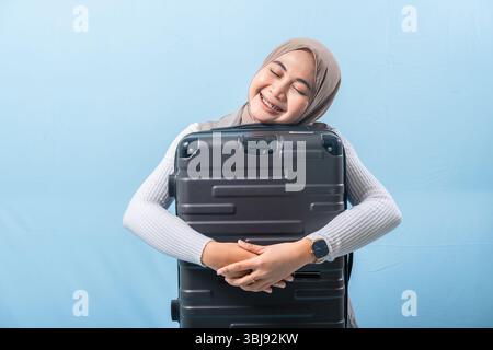 Une femme tient une valise noire et sourit. Concept d'aventure et d'excitation, comme la femme se prépare pour un voyage. Banque D'Images