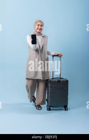 Une femme tient un téléphone portable noir et pointe vers lui. Elle sourit et elle est heureuse Banque D'Images