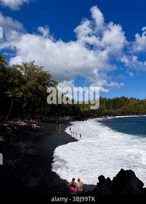 Les belles et magiques plages de sable noir sur la grande île de Hawai'i, États-Unis avec des roches de lave noire volcanique et des vagues qui s'écrasent. Banque D'Images
