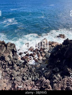Les belles et magiques plages de sable noir sur la grande île de Hawai'i, États-Unis avec des roches de lave noire volcanique et des vagues qui s'écrasent. Banque D'Images