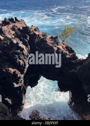 Les belles et magiques plages de sable noir sur la grande île de Hawai'i, États-Unis avec des roches de lave noire volcanique et des vagues qui s'écrasent. Banque D'Images