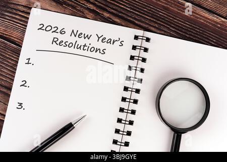 cahier avec écriture 'résolution du nouvel an 2026', stylo et loupe sur table en bois, concept de planification de la résolution du nouvel an et objectif personnel Banque D'Images