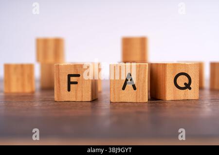 Bloc en bois avec FAQ écrite sur la table, concept de questions fréquemment posées, support client, assistance à l'information et service à l'utilisateur Banque D'Images