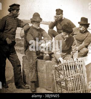 Whitby Yorkshire dans le passé - les pêcheurs locaux avec leurs tuyaux d'argile se détendent sur la jetée. Banque D'Images