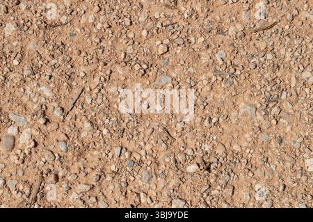 Texture de sol graveleux sec et sablonneux avec de petites pierres et cailloux - gros plan d'une surface de route en terre Banque D'Images