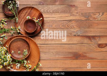 Composition avec différentes assiettes et fleurs de camomille fraîches sur fond en bois Banque D'Images