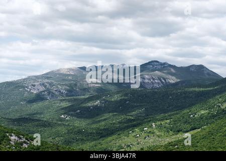 Des montagnes verdoyantes s'élèvent sous un ciel nuageux, mettant en valeur un paysage magnifique aux textures diverses et à la beauté naturelle. Banque D'Images