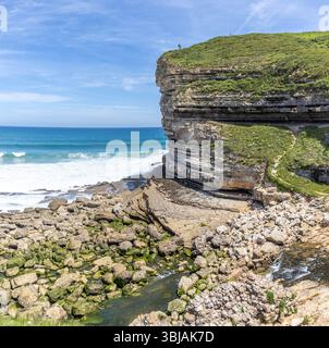 Acantilados de El Bolao, en la costa cantábrica. Las figuras humanas son pequeñas comparadas con la enormidad del acantilado. Alfoz de Lloredo, España Banque D'Images