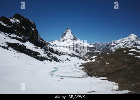 Zermatt, Suisse. 30 mai 2025. Le sommet pointu de la montagne contre le ciel bleu est le célèbre Matterhorn. Le lac gelé est le lac Riffel. Banque D'Images