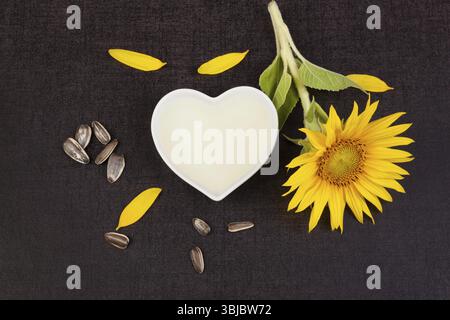 Huile de tournesol d'en haut avec plante de tournesol et graines sur fond noir Banque D'Images