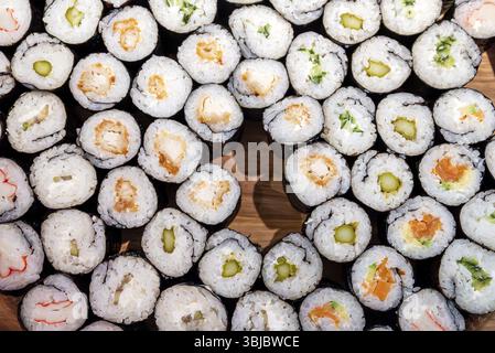 Beaucoup de différents types de sushis sur une assiette en bois Banque D'Images