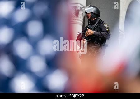 Los Angeles, États-Unis. 14 juin 2025. Un policier se tient sur les marches de l'hôtel de ville lors d'une manifestation "No Kings" dans le centre-ville de Los Angeles. Crédit : Maximilian Haupt/dpa/Alamy Live News Banque D'Images
