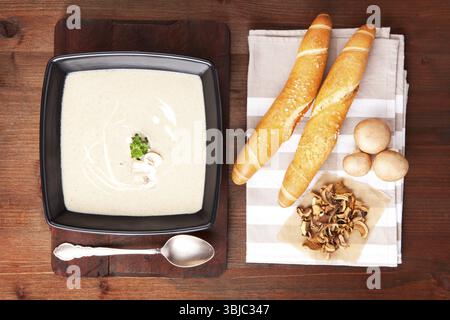 Délicieuse soupe à la crème de champignons dans un bol avec pâtisserie, champignons frais et séchés. Manger culinaire. Vue de dessus Banque D'Images