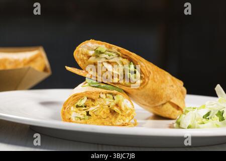 Tortillas enveloppent avec du curry de poulet et des légumes sur assiette blanche. Burrito au poulet. Nourriture saine Banque D'Images