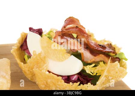 Panier de délicieux fromage parmigiano farci de salade fraîche, l'oeuf et bacon isolé sur fond blanc. Gastronomie culinaire Banque D'Images