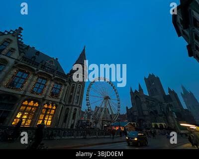 Grande roue festive derrière la cathédrale de Gand avec la lueur du marché de noël Banque D'Images