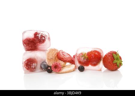 Fraises lyophilisées, framboises, groseilles, bleuets et bananes et baies congelées dans des glaçons isolés sur fond blanc Banque D'Images