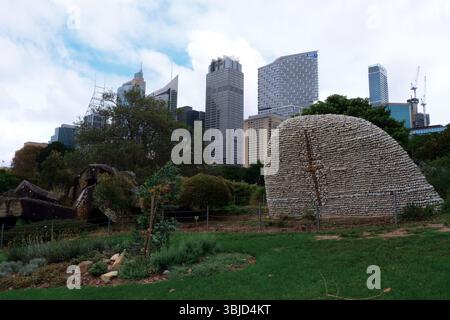 Sculpture Wurrungwuri et paysage urbain avec gratte-ciel de Sydney, Australie, pris des jardins botaniques royaux. Banque D'Images