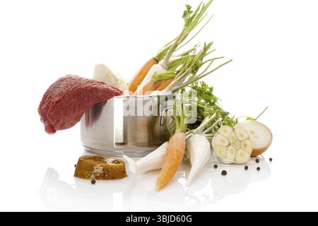 Ingrédients du bouillon dans un pot en argent isolé sur fond blanc. Cuisson au bouillon. Légumes frais en pot Banque D'Images