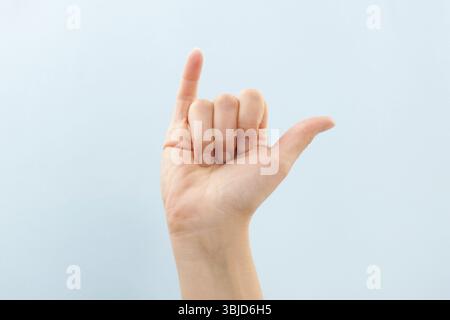 Langue des signes américaine. Main femelle montrant la lettre y isolée sur fond bleu Banque D'Images