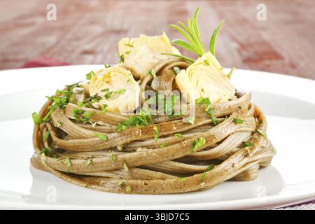 Pâtes avec des coeurs d'artichaut sur plaque blanche de gros plan. Cuisine culinaire de luxe Banque D'Images