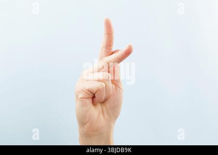 Langue des signes américaine. Main féminine montrant la lettre A isolée sur fond bleu Banque D'Images
