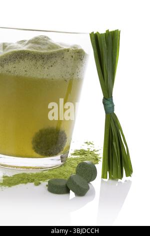 Comprimé effervescent vert se dissolvant dans l'eau. Pilules vertes, poudre verte et brins d'herbe isolés sur fond blanc. Détox naturelle. Algues saines Banque D'Images