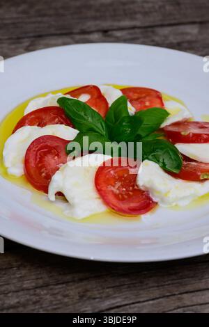 Salade Insalata Caprese avec Mozzarella di Bufala Campana, tomates rouges et feuilles de basilic vert habillées d'huile d'olive extra vierge Banque D'Images