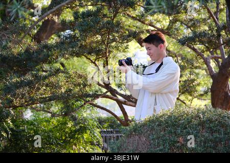 jeune homme prendre des photos utilisez un appareil photo sans miroir au printemps Banque D'Images