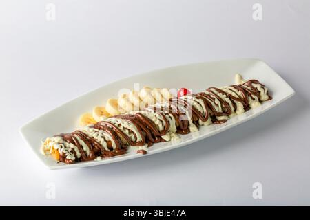 Crêpe au chocolat de luxe avec tranches de banane, dessert occidental isolé sur fond blanc. Banque D'Images